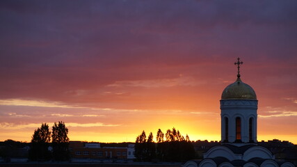The dome of the church on the background of a sunset in summer