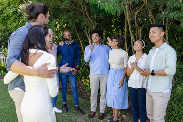 Friends celebrating outdoors, smiling and clapping at wedding gathering in garden