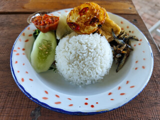 Tempong rice, Tempong rice is equipped with fresh vegetables, salted fish, eggs, chili sauce, tempeh, tofu and other accompaniments. Tempong rice is a typical food from Banyuwangi, Indonesia.