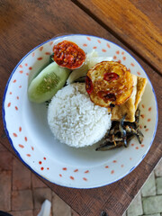 Tempong rice, Tempong rice is equipped with fresh vegetables, salted fish, eggs, chili sauce, tempeh, tofu and other accompaniments. Tempong rice is a typical food from Banyuwangi, Indonesia.