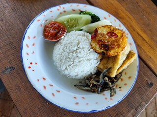 Tempong rice, Tempong rice is equipped with fresh vegetables, salted fish, eggs, chili sauce, tempeh, tofu and other accompaniments. Tempong rice is a typical food from Banyuwangi, Indonesia.