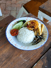 Tempong rice, Tempong rice is equipped with fresh vegetables, salted fish, eggs, chili sauce, tempeh, tofu and other accompaniments. Tempong rice is a typical food from Banyuwangi, Indonesia.