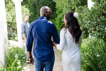 Bride and groom walking arm in arm through lush garden, smiling joyfully