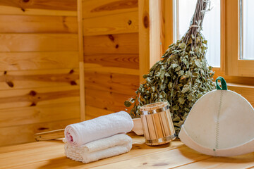 Sauna equipment. Bucket, ladle, felt wool hat and towel on bamboo bench
