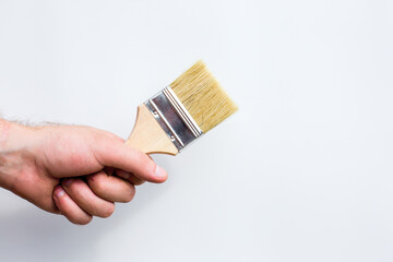 A paint brush in a man's hand. Renovation concept. Supplies and tools for painting walls isolated on white