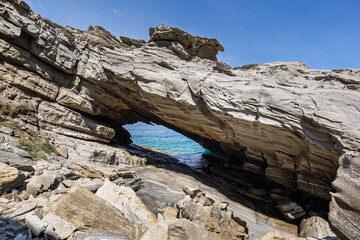 Stunning and big natural arc by the sea at the Paros Park on Paros island in Greece on a sunny day. Rocky geological landscape and natural attraction.