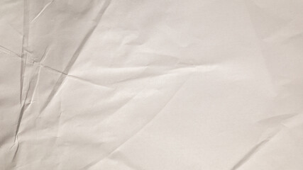 A large, crumpled sheet of white paper lays flat, displaying intricate folds and textures that create a visually interesting surface, inviting creative exploration and interpretation