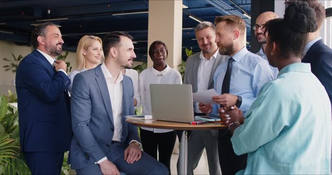 Group of business people working together in the office during a meeting, celebrating success and supporting colleague. The team is applauding, showcasing collaborative and positive work environment.