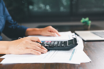 Office businesswoman hand to operate calculator analyzing financial data, counting costs on desk....