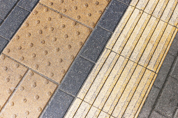 Tactile paving surface closeup. Yellow tiles with guiding lines. Textured pedestrian path for blind...