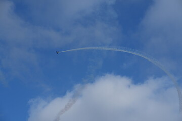 Small Airplane with a White Smoke Trail Against a Cloudy Sky