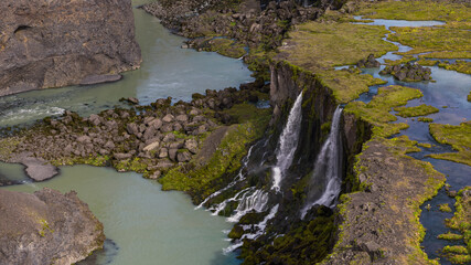 Aerial View of Waterfall Cascading Over Moss Covered Cliff in Iceland