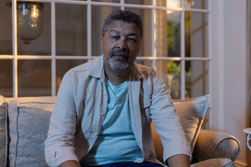 Naklejka premium Senior man relaxing on sofa at home, looking content and thoughtful
