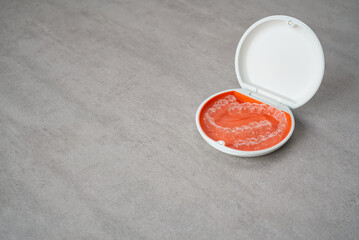 Orthodontic aligner and orange case placed on the table.　Dental orthodontic mouthpiece.