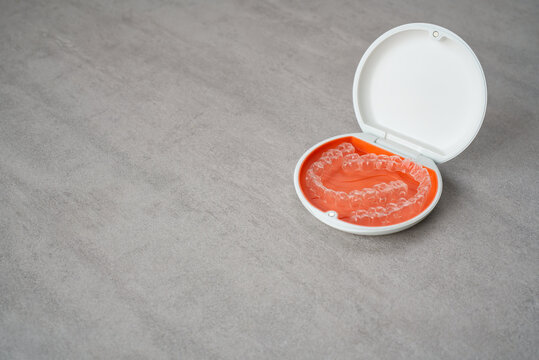 Orthodontic aligner and orange case placed on the table.　Dental orthodontic mouthpiece.