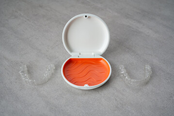 Orthodontic aligner and orange case placed on the table.　Dental orthodontic mouthpiece.