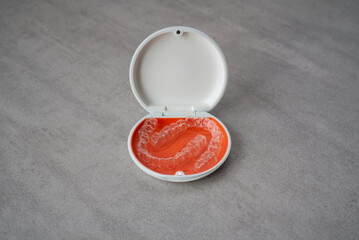 Orthodontic aligner and orange case placed on the table.　Dental orthodontic mouthpiece.