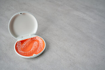 Orthodontic aligner and orange case placed on the table.　Dental orthodontic mouthpiece.