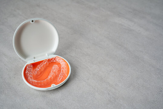 Orthodontic aligner and orange case placed on the table.　Dental orthodontic mouthpiece.