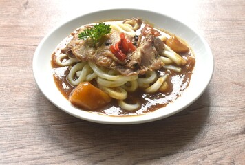 slice roasted chicken topping udon or Japanese rice noodles dressing potato and carrot in Japanese curry on plate 