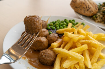 Meatballs with french fries, green peas, bechamel sauce and cranberry jam