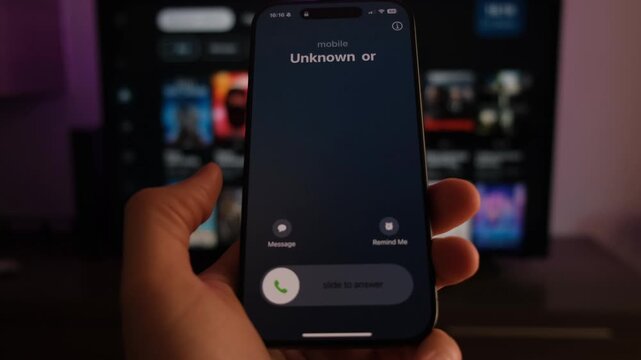 Close-up of a smartphone screen receiving a call from an unknown number, held in hand indoors.