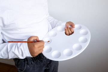 Young caucasian child with paint palette and brush