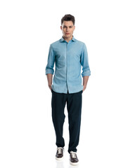 confident casual guy in denim shirt walking with hands in pockets