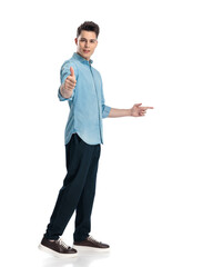 attractive young man pointing finger to side and making thumbs up gesture