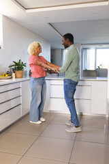 Friends laughing and dancing together in modern kitchen, enjoying happy moments