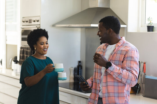 African American friends in kitchen enjoying coffee and conversation, smiling warmly - Powered by Adobe