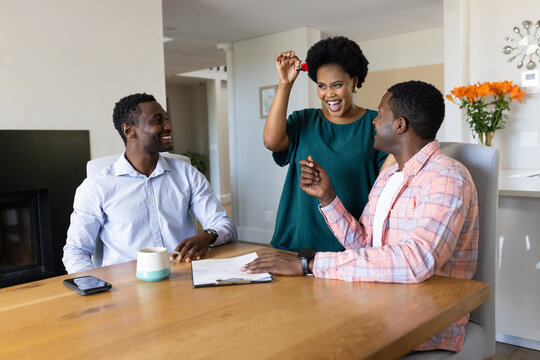 African American friends celebrating new home purchase with keys at dining table