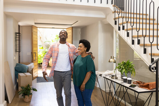 Happy couple entering new home, smiling and embracing in bright hallway