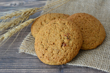 Oatmeal Cookies on Burlap and Wood Surface decorated with ears of wheat