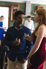 Teenagers having drinks and chatting at lively school party gathering