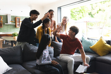 Teenagers high-fiving and celebrating success together in modern living room