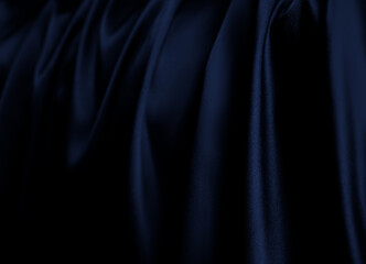 Flowing down, hanging silk. Curtain, stage clothes. Luxurious dark black cobalt, space blue, navy satin fabric with elegant, flowing drapes and soft sheen. Premium cloth texture with wavy folds.