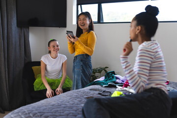 Teen girls laughing and chatting while planning outfits in cozy bedroom