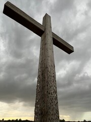 Landscape of large wooden cross at the ruin site of catholic St Benet's Abbey on Norfolk Broads uk in stormy weather, look upwards to cloudy sky a conceptual image of faith by altar for mass outdoors