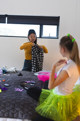 Preparing outfits for celebration, teen girls in bedroom exploring creative fashion choices