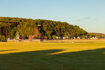View of the 1908 railway trestle bridge and nautical park installations in the Cap-Rouge waterfront seen during a late summer sunny afternoon, with low tide grasses in the foreground, Quebec City