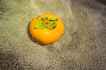 Naklejka premium Ripe persimmon fruit isolated, top view, fluffy gray fabric background.
