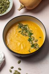 Delicious autumn pumpkin soup garnished with seeds and chives for cozy comfort. Autumn menu. 