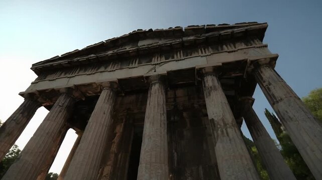 Ancient Greek temple ruin with tall Doric columns and a triangular pediment, sun peeking from the left.