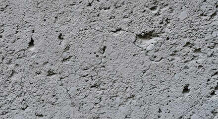 Fototapeta premium Detailed macro shot of a rough gray cement wall, showcasing its porous texture, fine cracks, and weathered surface for an abstract background