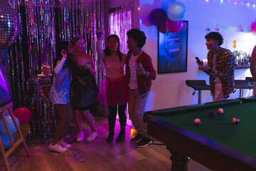 Teenagers celebrating at home, enjoying party with music and colorful decorations