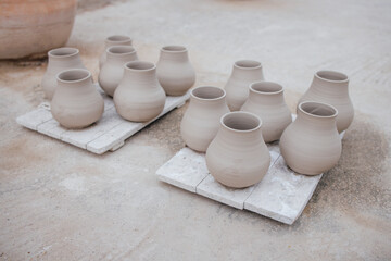 Group of handcrafted clay pots arranged on wooden pallets, showcasing unique shapes and textures,...