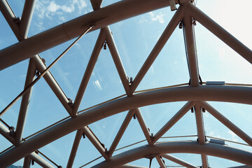 Architectural design featuring a glass and steel structure against blue sky during daylight hours