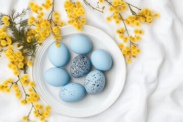 Elegant blue easter eggs arranged on white plate surrounded by bright yellow mimosa blooms, perfect for spring celebrations