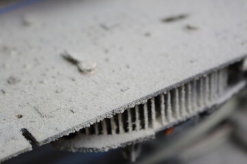 A detailed shot of a grimy metal computer fan resting on a clean white tabletop, reminiscent of automotive tire components like alloy wheels, rims, and hubcaps